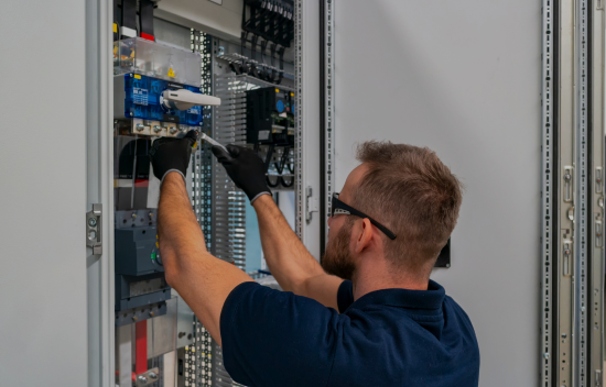 Técnico electricista trabajando en el interior de un cuadro eléctrico